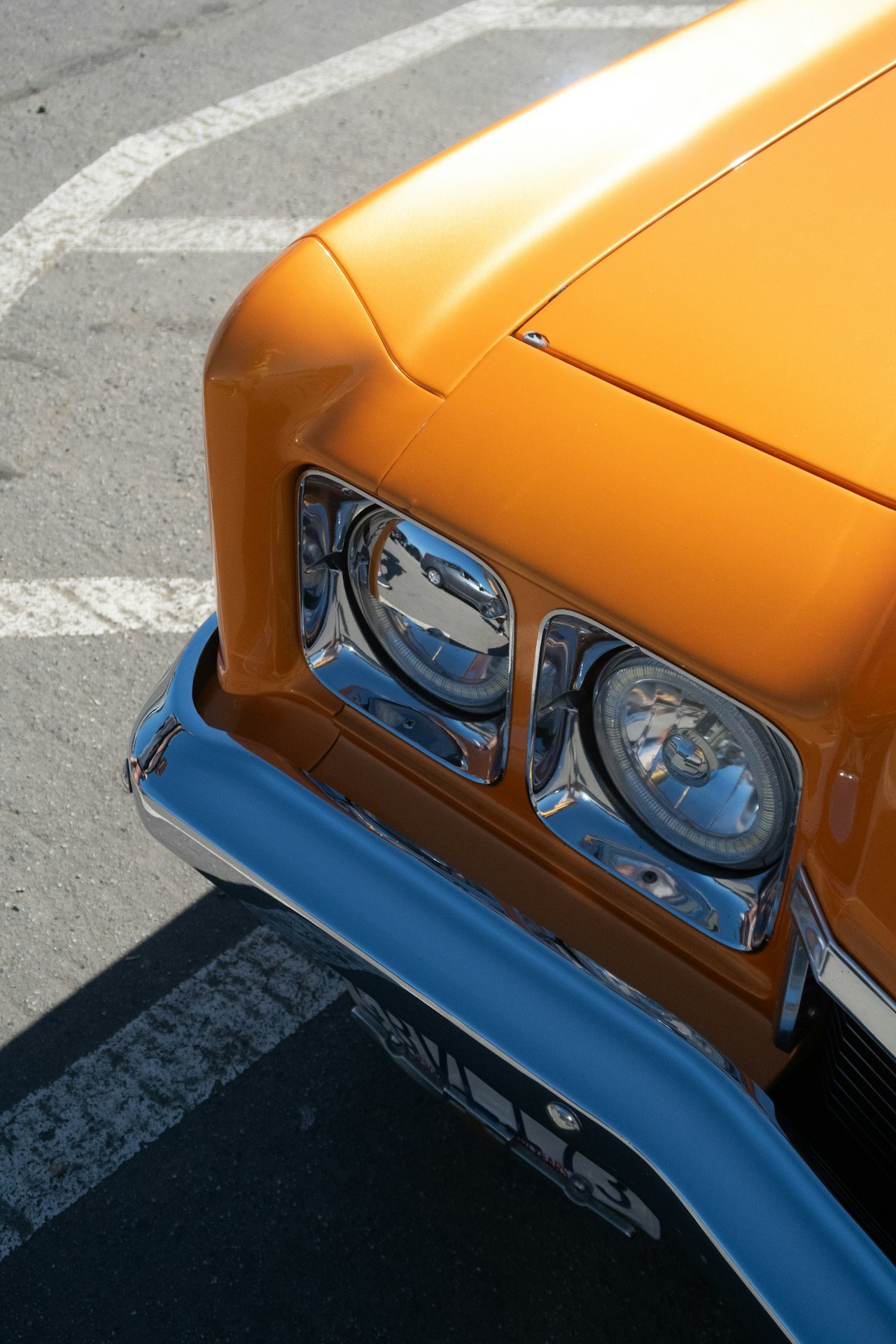 Close-up of classic car bodywork showing orange paint and chrome trim details