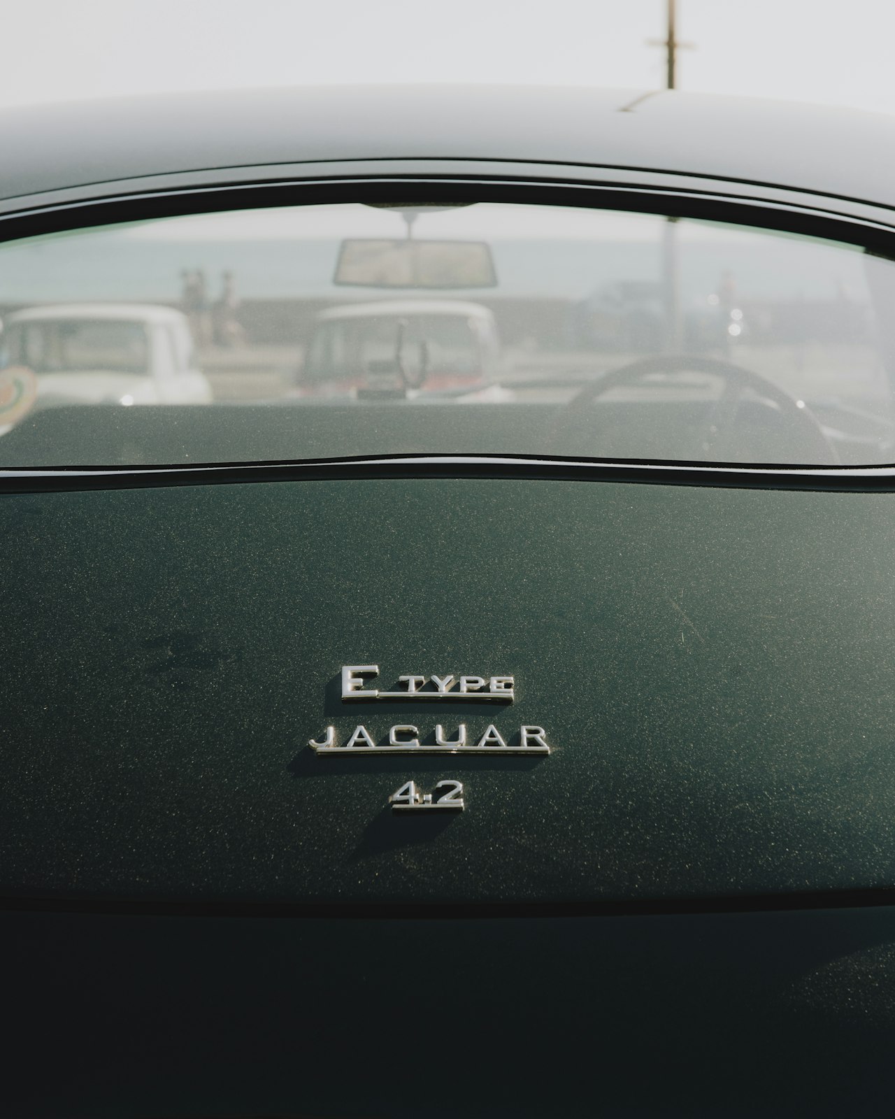 Rear badge of a British Racing Green Jaguar E-Type showing the E Type, Jaguar, and 4.2 chrome lettering