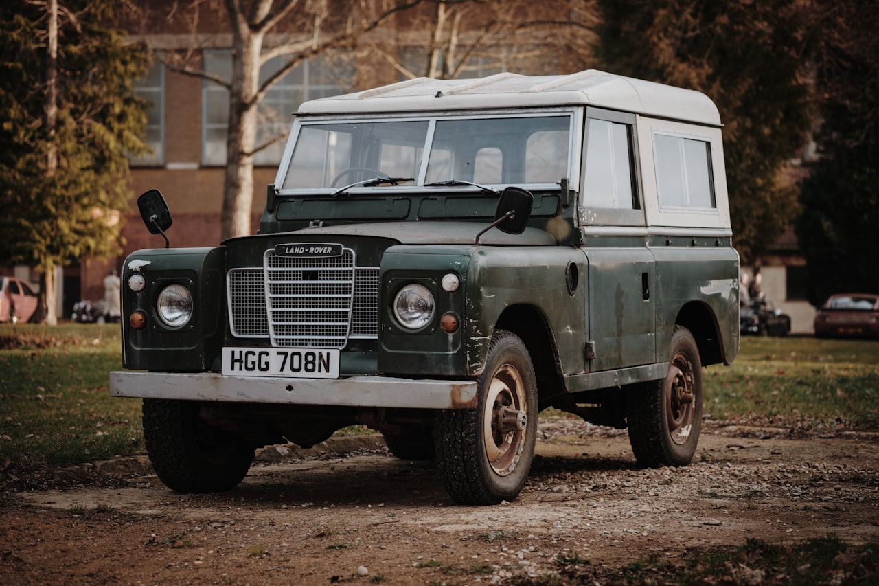 Green and white Land Rover SUV driving on a country road