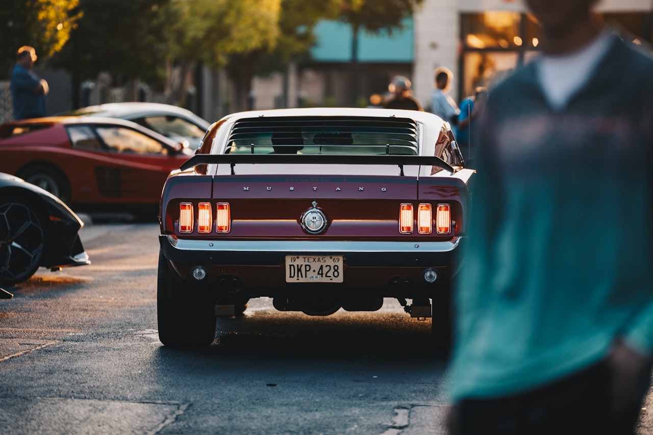 Classic red Ford Mustang at sunset, showcasing the iconic pony car profile