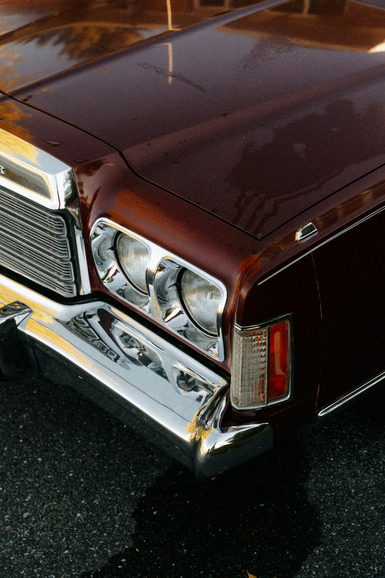 Close-up front corner of a dark burgundy classic American car from the early 1970s