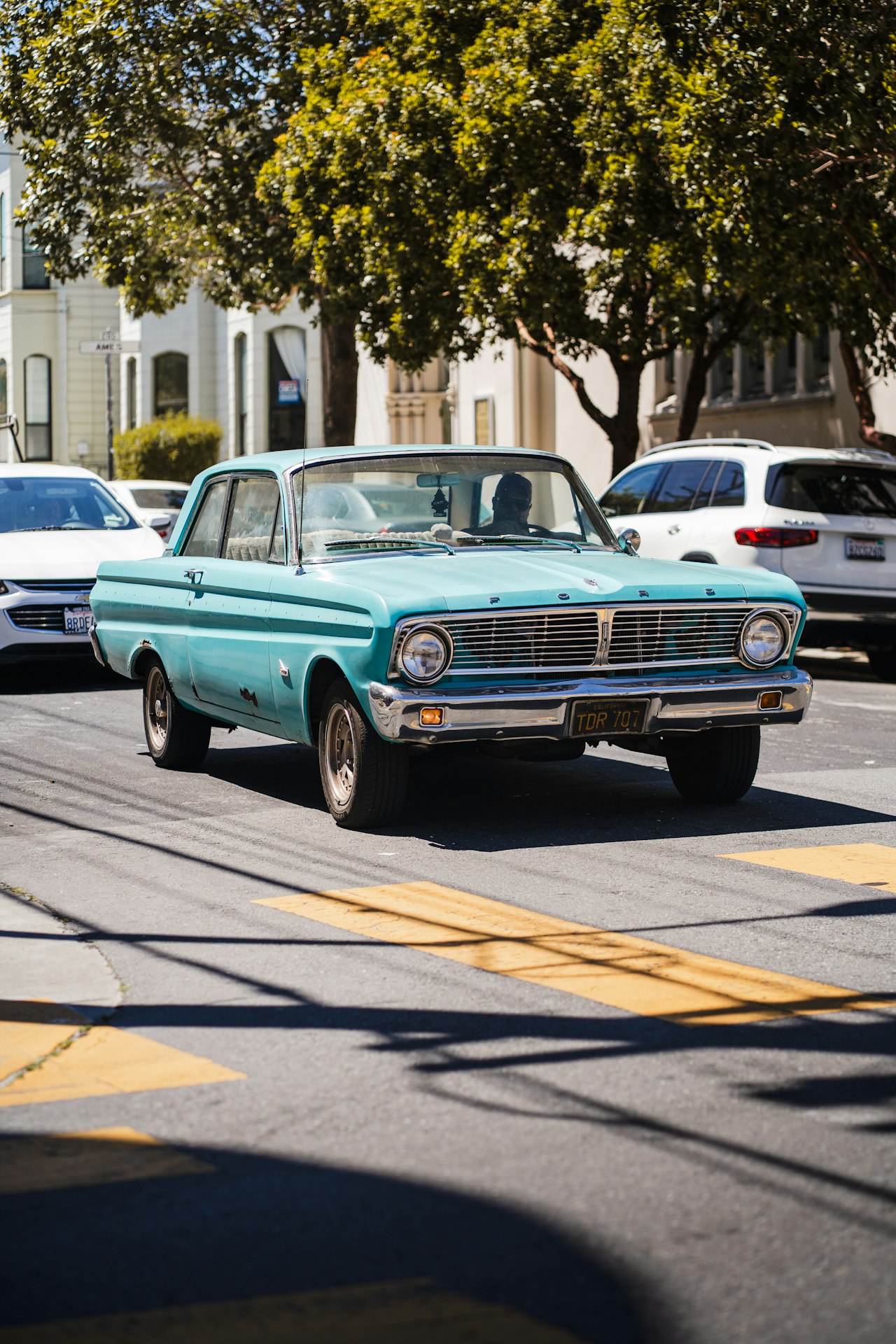 Vintage teal classic car parked on a tree-lined street
